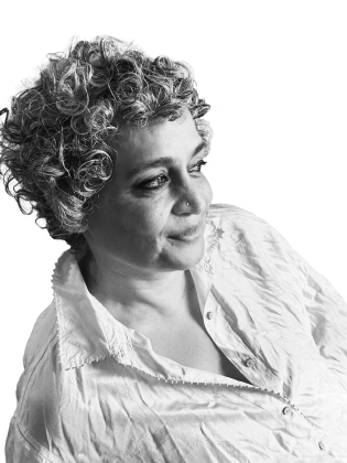 Kvinna med kort lockigt hår i vit skjorta, ser åt sidan på porträtt mot vit bakgrund.