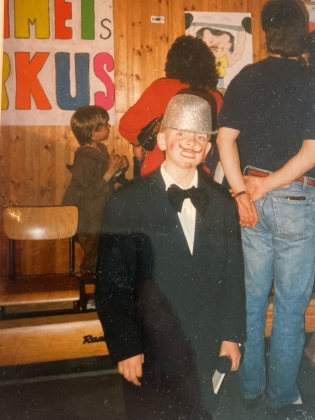 En ung pojke i glittrig hatt, målad mustach och kostym